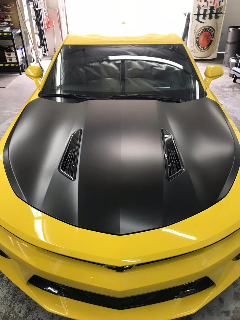 Head-on at the matte black hood over yellow — the hard line down the middle is all install work.