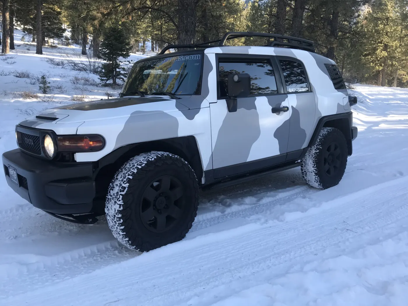 SUV in a printed winter camouflage, photographed out of town in the snow.