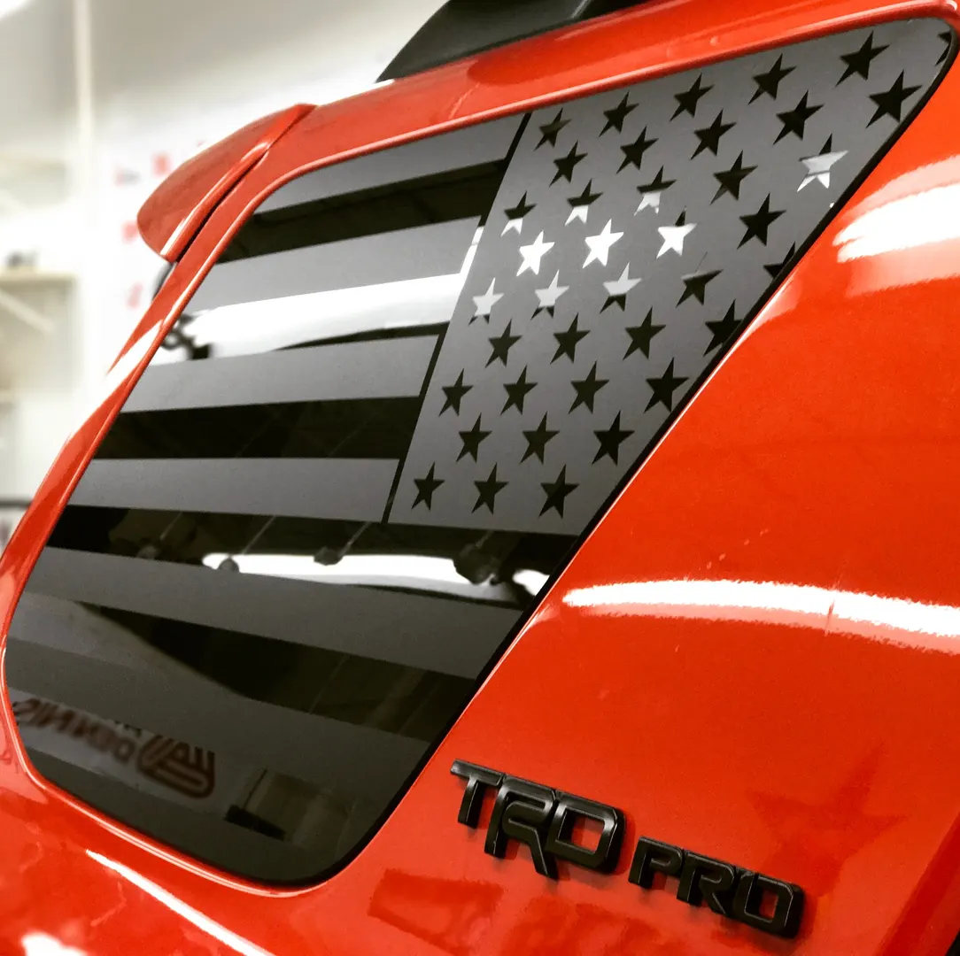 Perforated flag graphic across the rear quarter glass of a pickup.