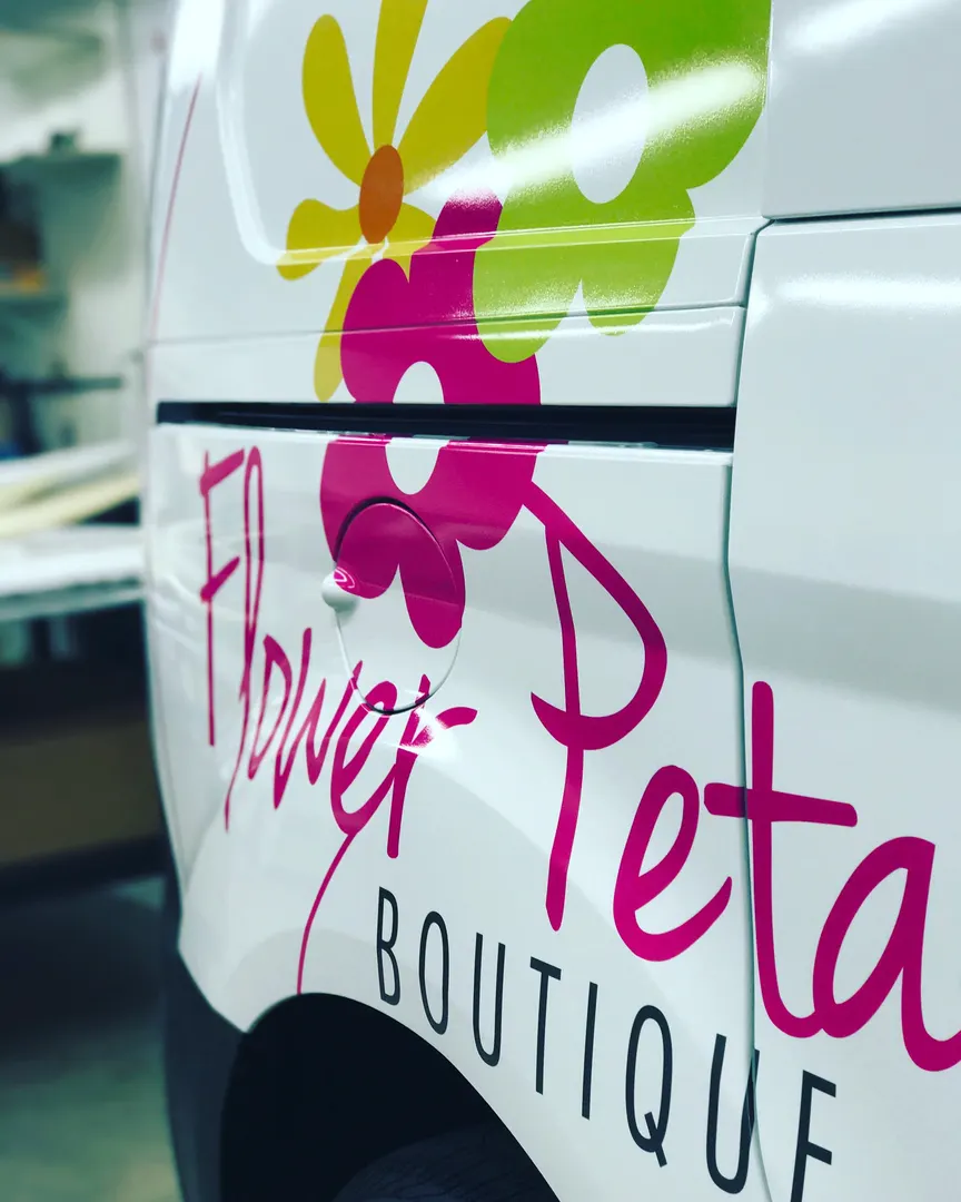 Cargo van in a floral print with script lettering — a wrap doing the job of a shopfront.