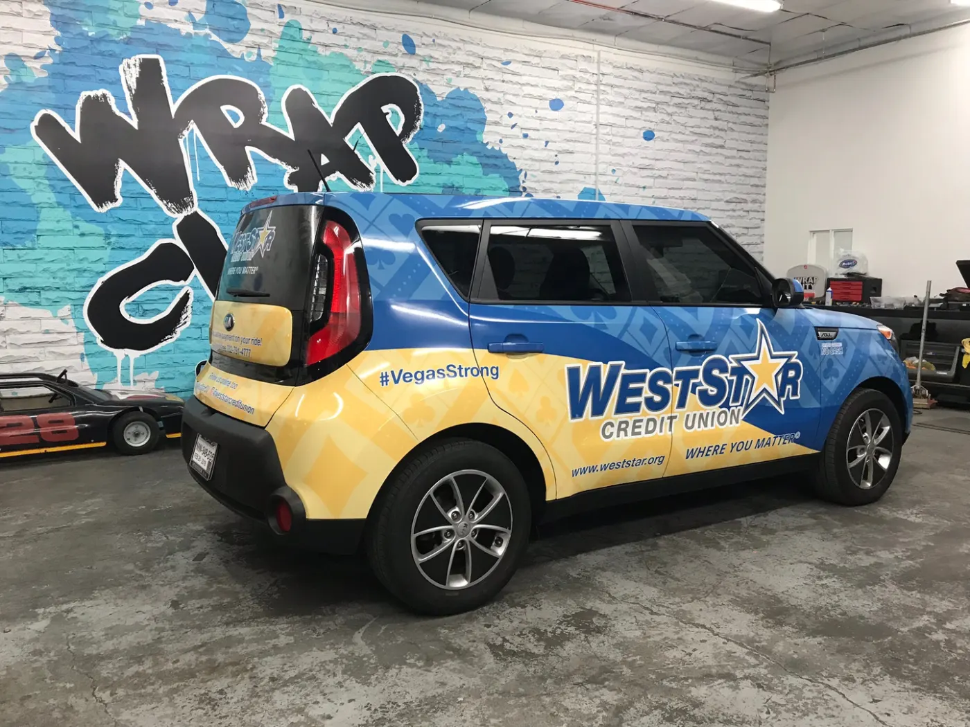 Compact crossover wrapped corner to corner in a two-colour print, shot in the bay against the logo wall.